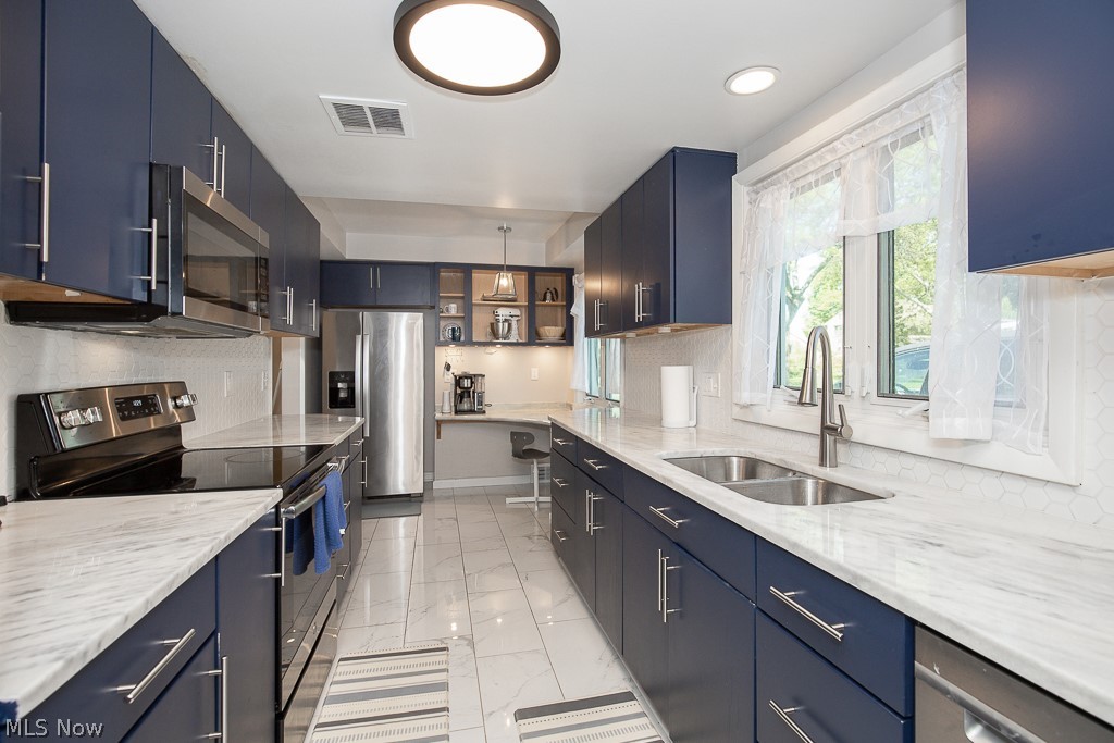 21825 Rye Road Beachwood, OH 44122 - Photo 12 of 35 Kitchen featuring pendant lighting, light stone countertops, appliances with stainless steel finishes, sink, and blue cabinets