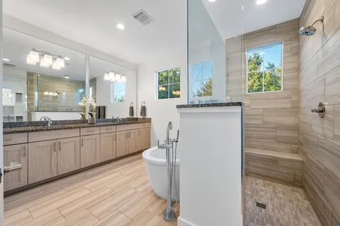 a spacious bathroom with a double vanity sink a mirror and a bathtub