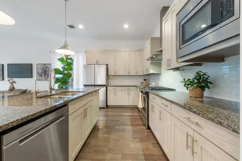 a kitchen with granite countertop white cabinets and stainless steel appliances