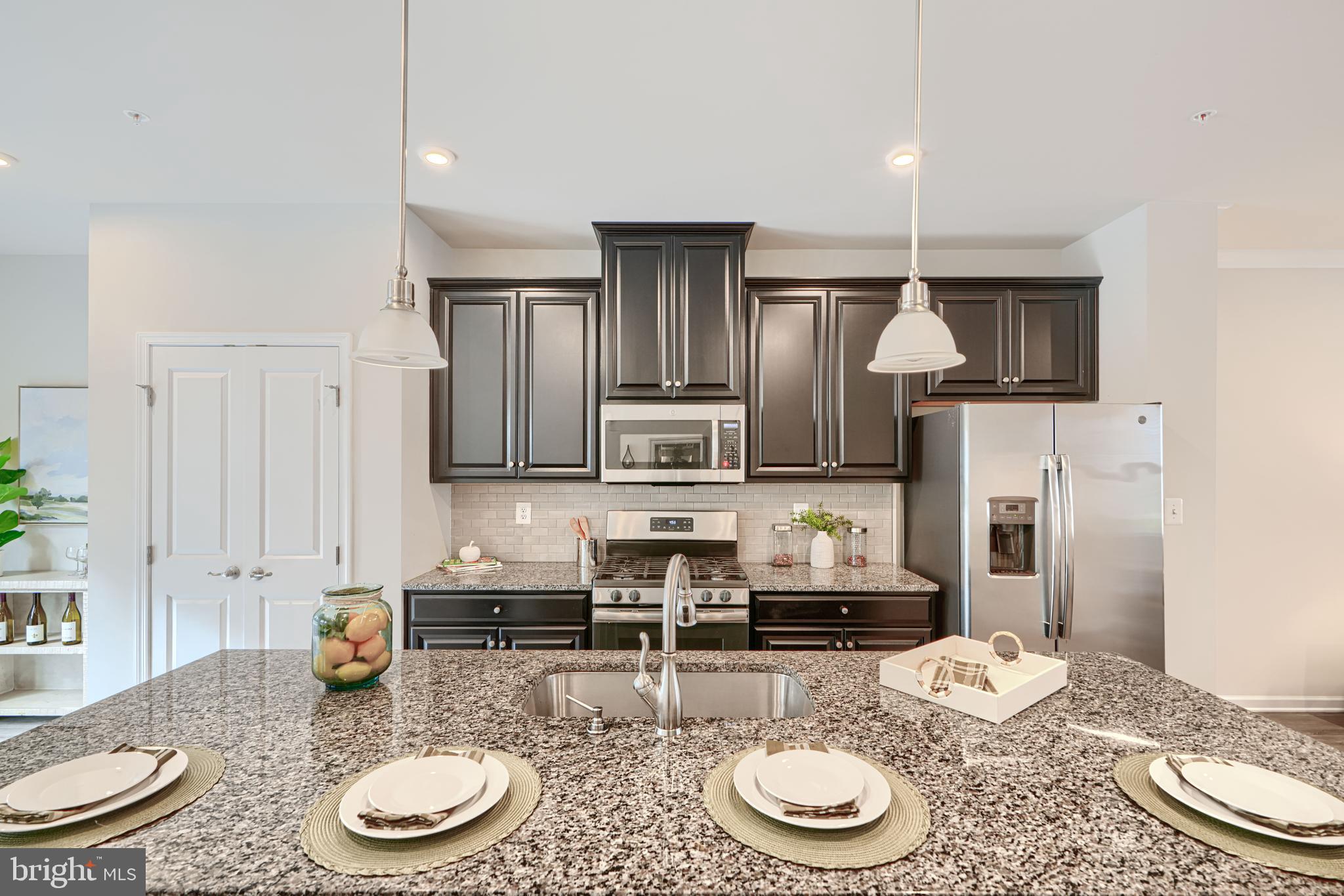 2824 Shaws Road Sparrows Point, MD 21219 - Photo 14 of 61 a kitchen with stainless steel appliances granite countertop a sink a stove a kitchen island with chairs and wooden floor