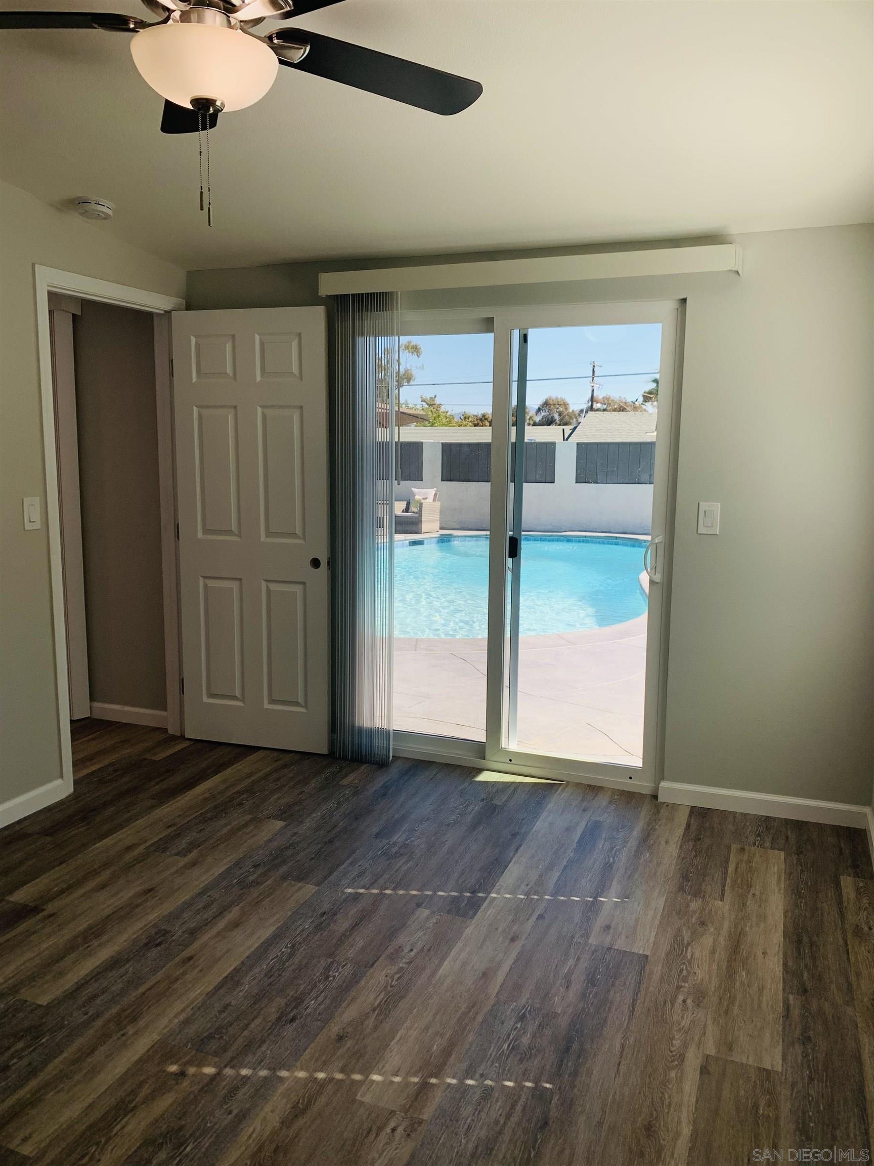 377 El Monte Road El Cajon, CA 92020 - Photo 4 of 19 an empty room with wooden floor chandelier fan and windows