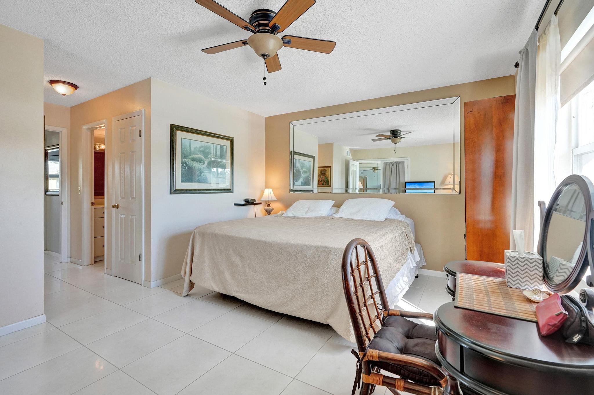 231 East Lantana Road, Unit 204 Lantana, FL 33462 - Photo 11 of 63 a spacious bedroom with a bed a chandelier and mirror