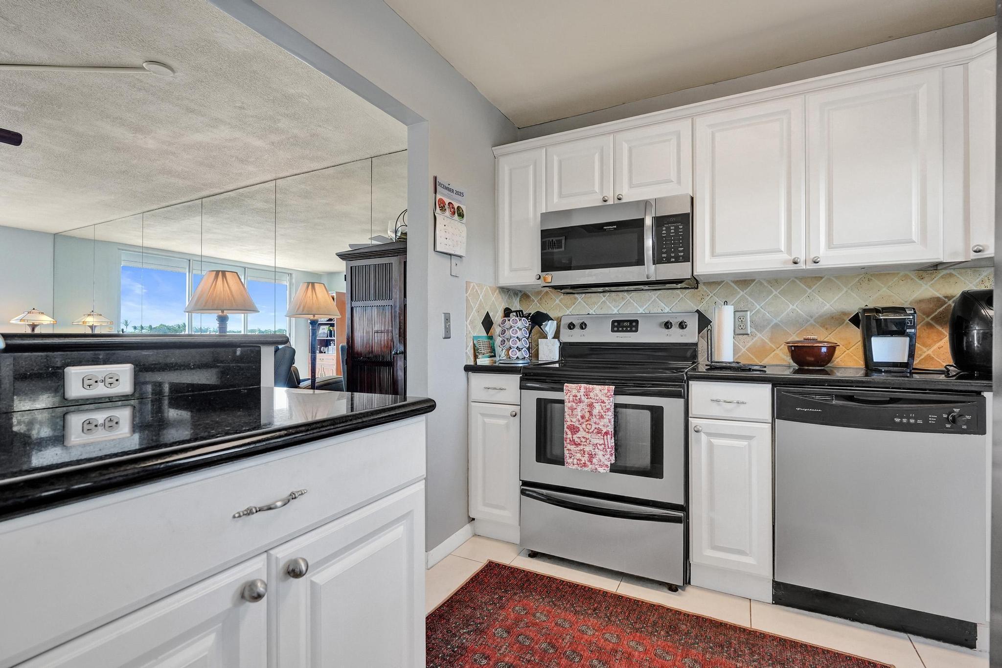 231 East Lantana Road, Unit 204 Lantana, FL 33462 - Photo 32 of 63 a kitchen with stainless steel appliances granite countertop a refrigerator a stove a sink and white cabinets