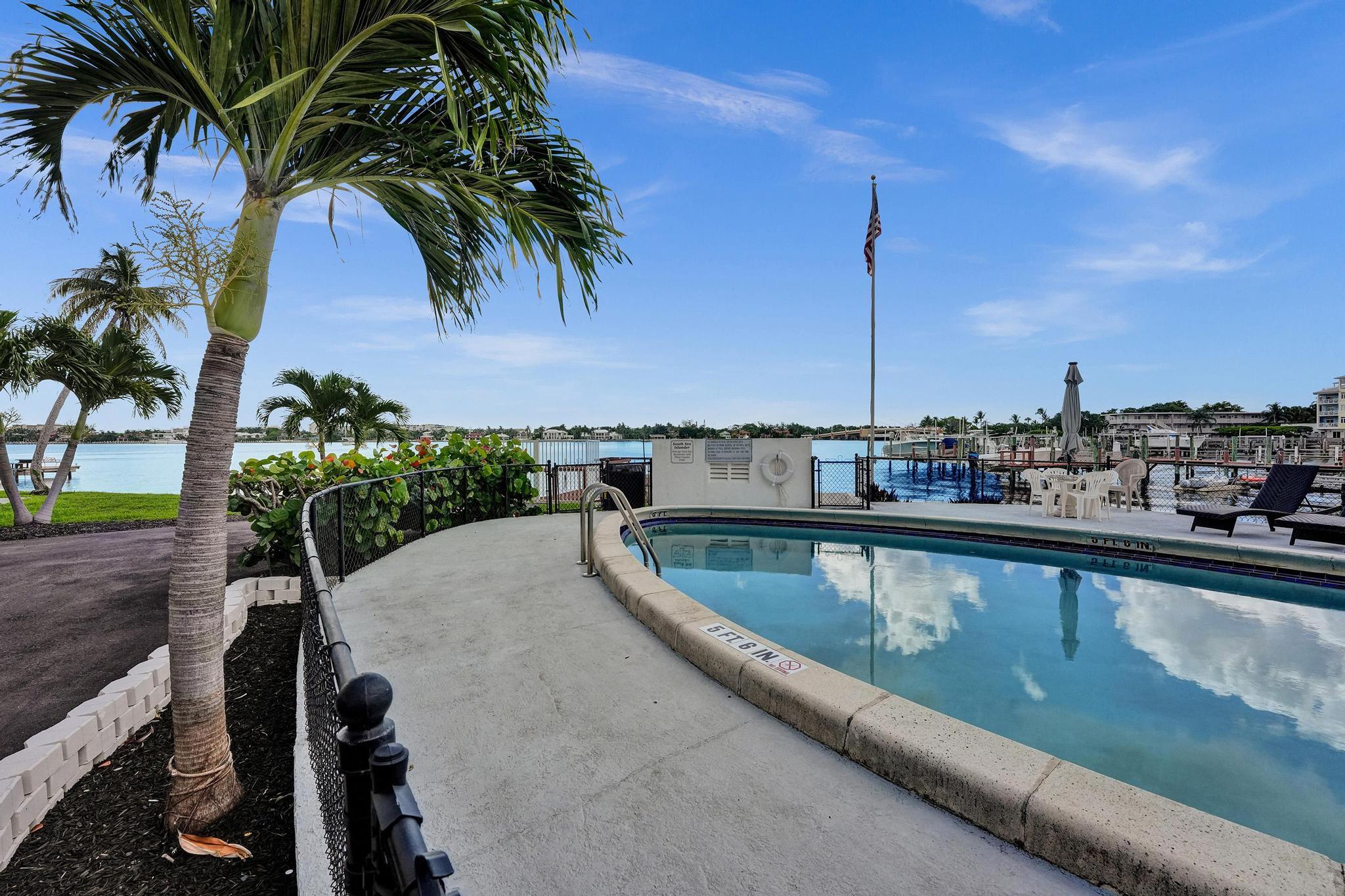 231 East Lantana Road, Unit 204 Lantana, FL 33462 - Photo 56 of 63 a view of a swimming pool with a lawn chairs under an umbrella
