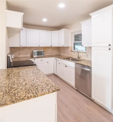 a kitchen with granite countertop sink stove and cabinets