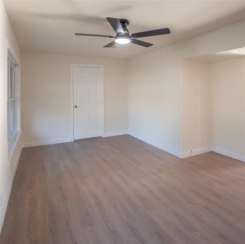 a view of an empty room with a window and wooden floor