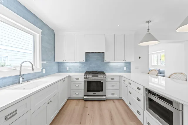a kitchen with white cabinets and sink