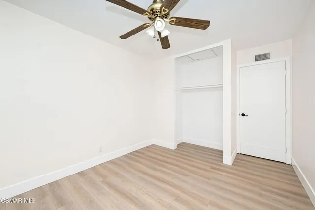 a view of a room with wooden floor and a ceiling fan