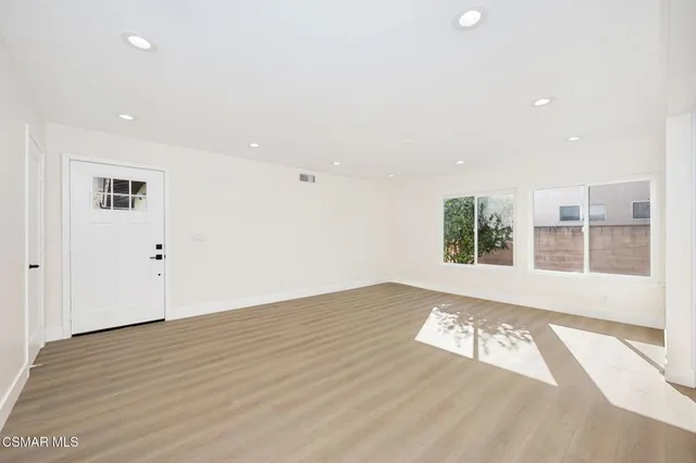 a view of an empty room with wooden floor and a window