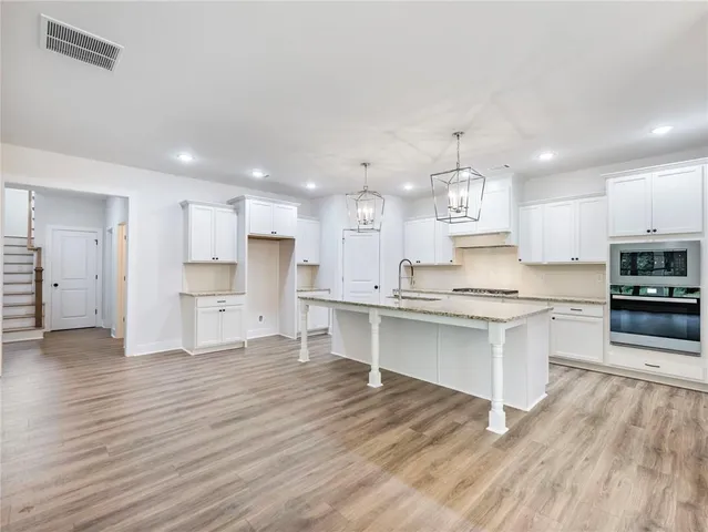 a large kitchen with stainless steel appliances granite countertop a stove a sink dishwasher and a oven with white cabinets