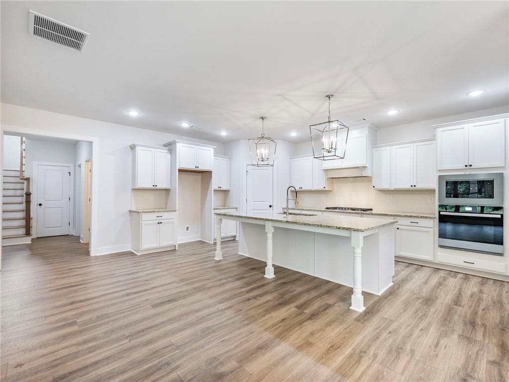 490 Jackson Street Buford, GA 30518 - Photo 13 of 46 a large kitchen with stainless steel appliances granite countertop a stove a sink dishwasher and a oven with white cabinets