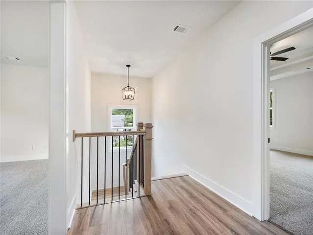 a view of a hallway with wooden floor and a bathroom