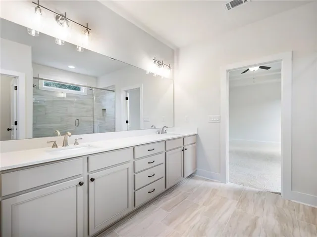 a spacious bathroom with a double vanity sink a mirror and a shower