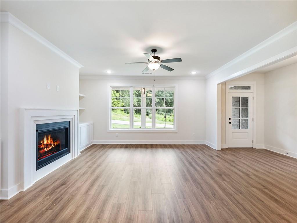 490 Jackson Street Buford, GA 30518 - Photo 5 of 46 an empty room with wooden floor fireplace cabinet and windows