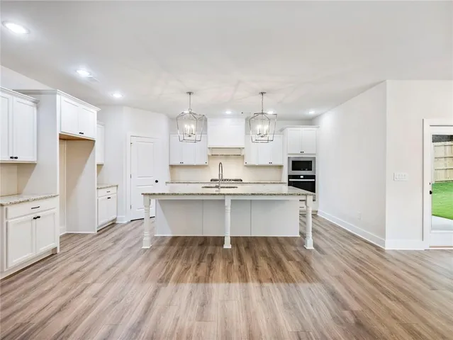 a large white kitchen with a refrigerator a sink dishwasher a stove and white countertops with wooden floor