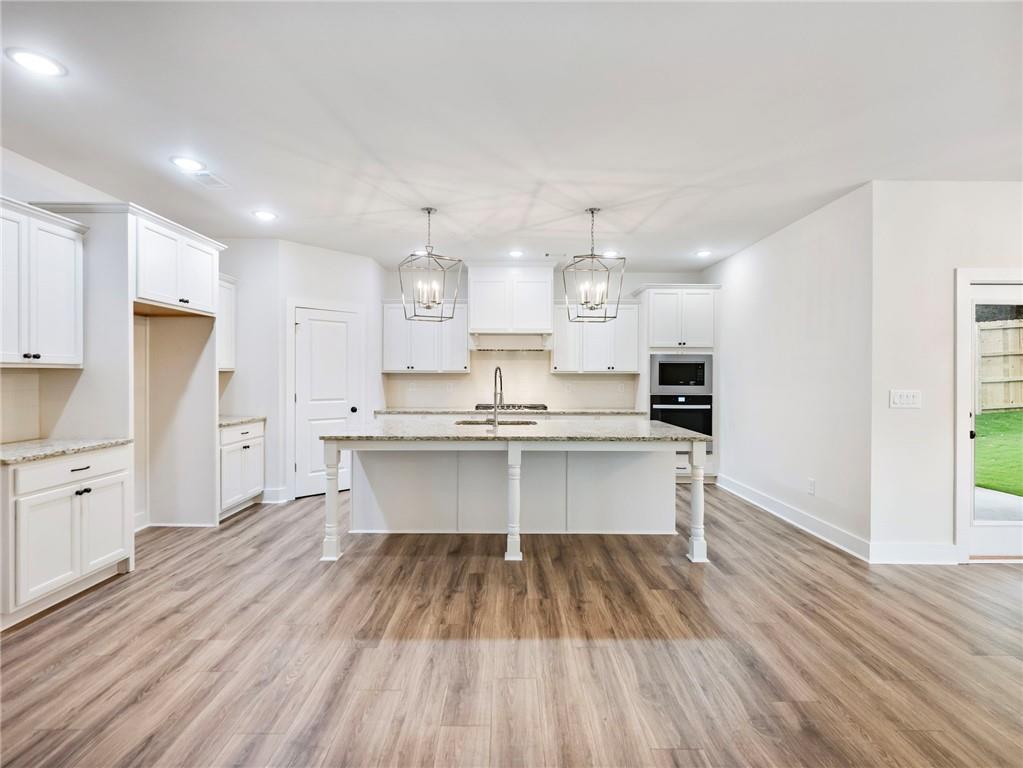 490 Jackson Street Buford, GA 30518 - Photo 6 of 46 a large white kitchen with a refrigerator a sink dishwasher a stove and white countertops with wooden floor