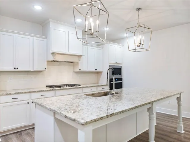 a kitchen with stainless steel appliances granite countertop a sink dishwasher and white cabinets with wooden floor