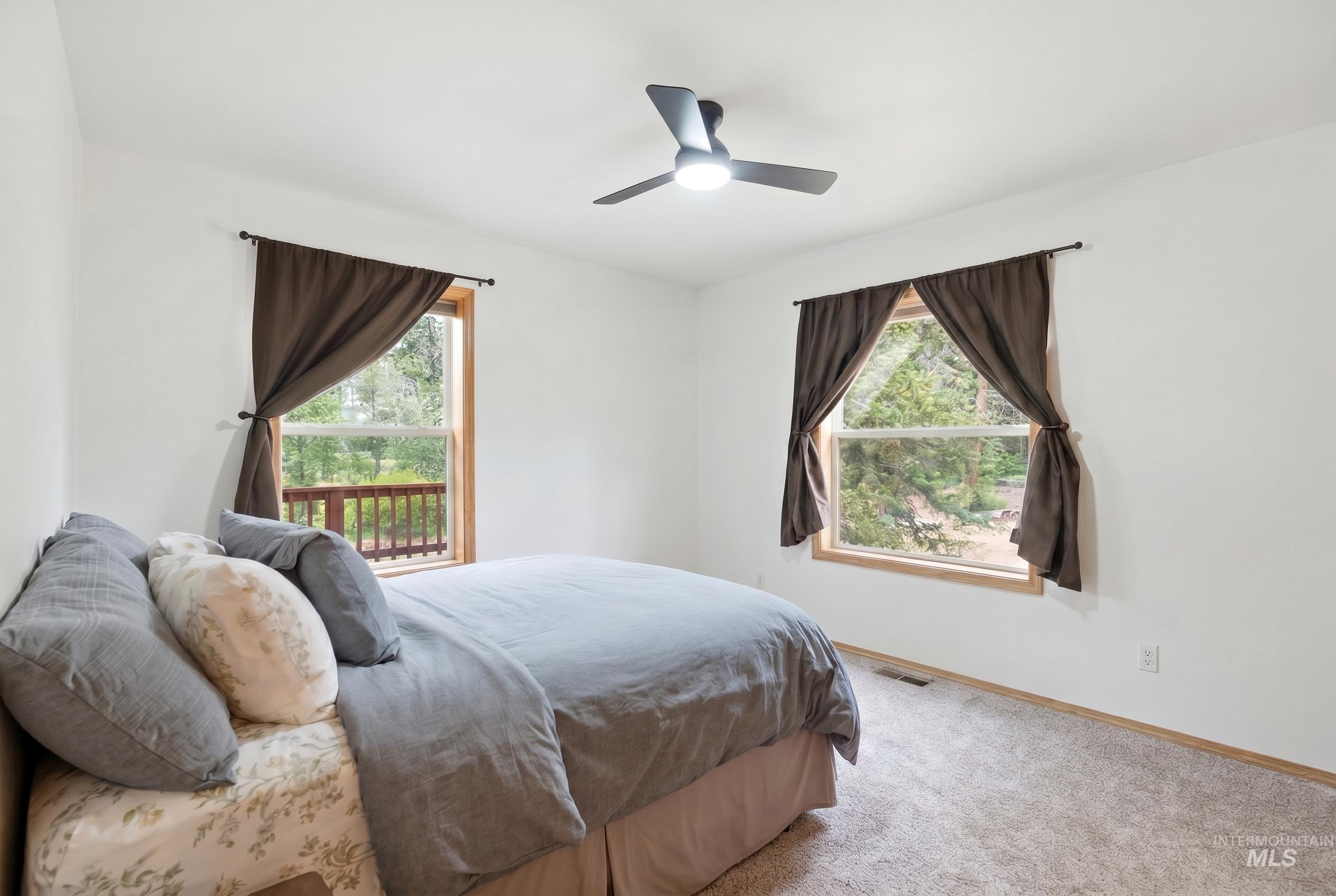 3980 North Pine-Featherville Road Mountain Home, ID 83647 - Photo 16 of 35 Carpeted room with two large windows featuring wood-finish trim and brown drapes