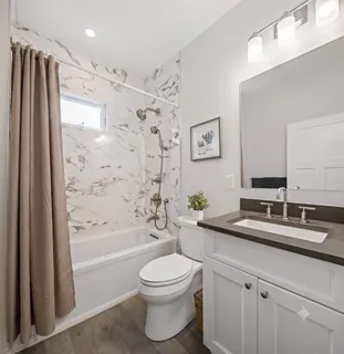 a bathroom with a granite countertop sink toilet a large mirror a bathtub and shower