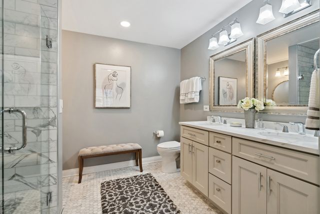 a spacious bathroom with a double vanity sink a toilet and a mirror