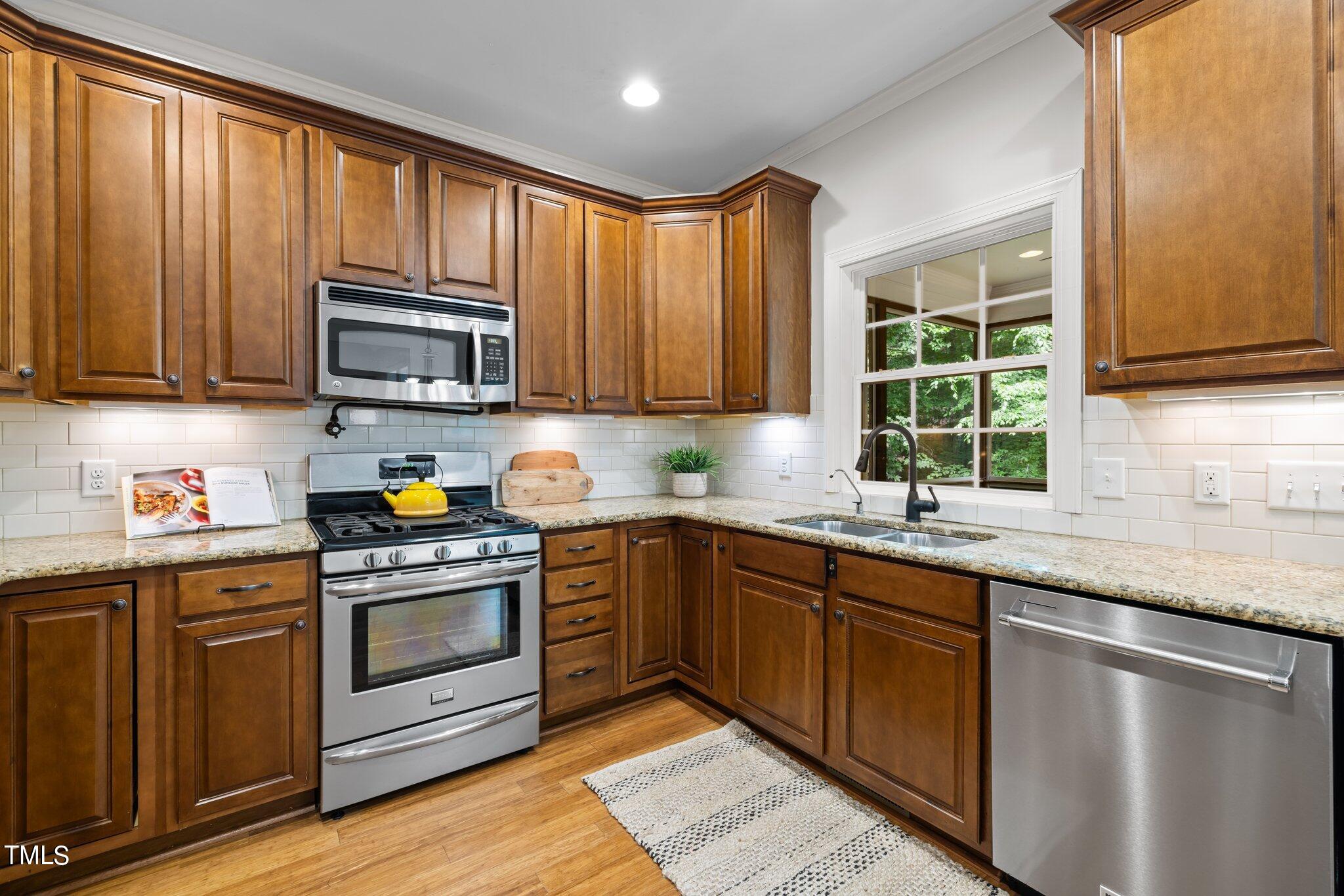 152 Roads End Pittsboro, NC 27312 - Photo 15 of 58 a kitchen with granite countertop wooden cabinets a sink a stove a window and stainless steel appliances