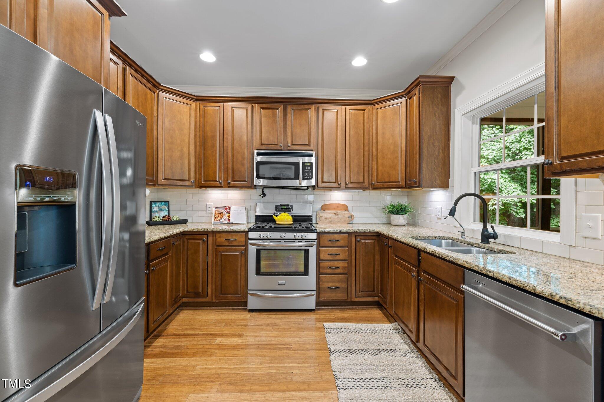 152 Roads End Pittsboro, NC 27312 - Photo 16 of 58 a kitchen with stainless steel appliances granite countertop a refrigerator a sink dishwasher a stove top oven a large window with a dining table and chairs