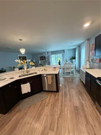 a large white kitchen with a large counter top a sink a stove and wooden floor