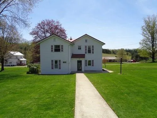 a view of a house with a big yard with plants and large trees