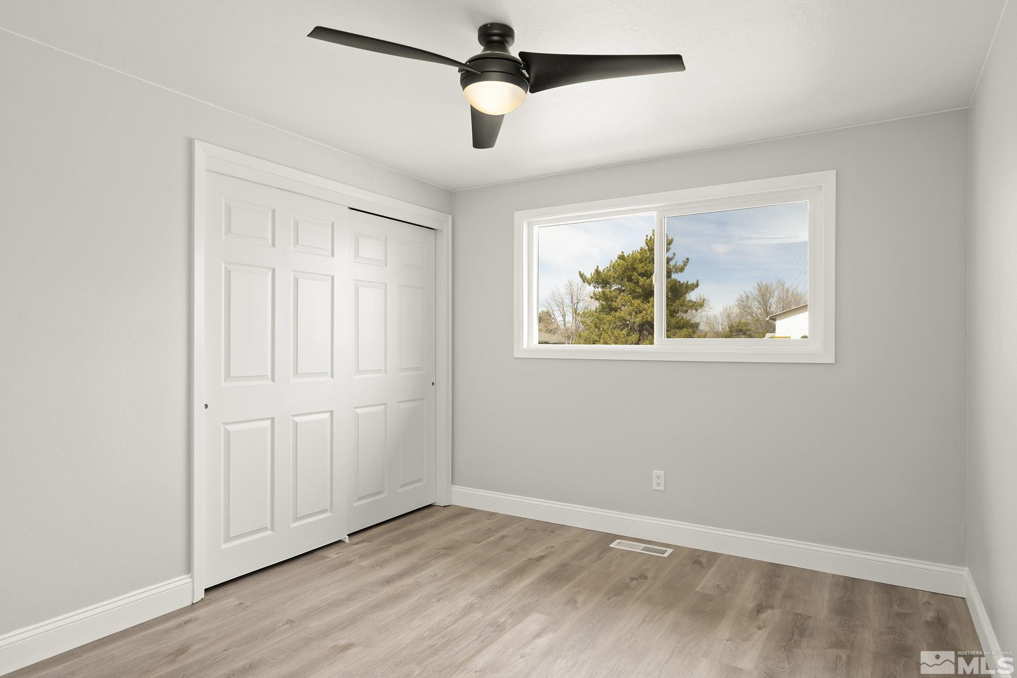 8895 Limnol Street Reno, NV 89506 - Photo 13 of 21 an empty room with wooden floor ceiling fan and windows