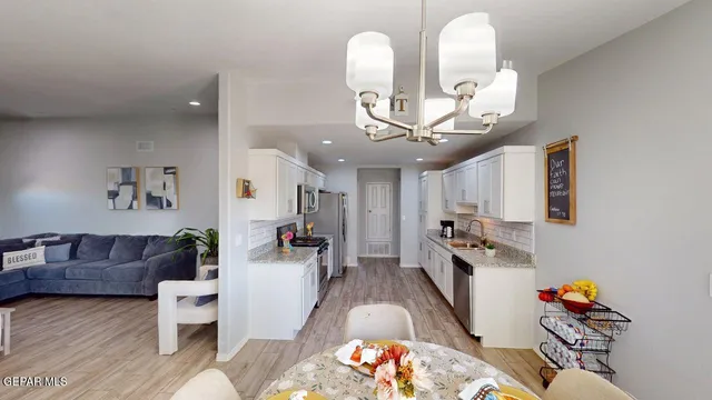 a kitchen with stainless steel appliances a stove top oven a sink a refrigerator white cabinets and wooden floor