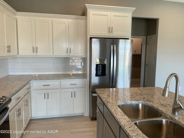 a kitchen with white cabinets a sink and stainless steel appliances
