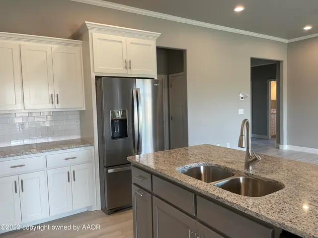 a kitchen with granite countertop a sink and refrigerator
