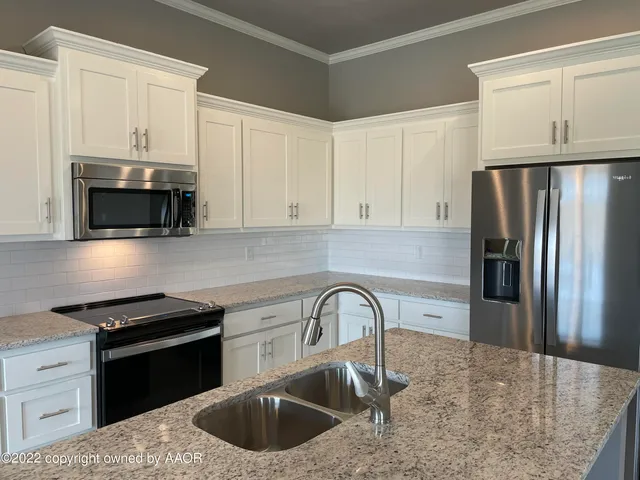 a kitchen with stainless steel appliances granite countertop a sink a stove a microwave and refrigerator