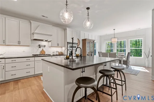 a kitchen with stainless steel appliances kitchen island granite countertop a dining table chairs and white cabinets