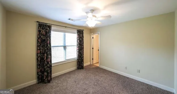 an empty room with windows and chandelier fan