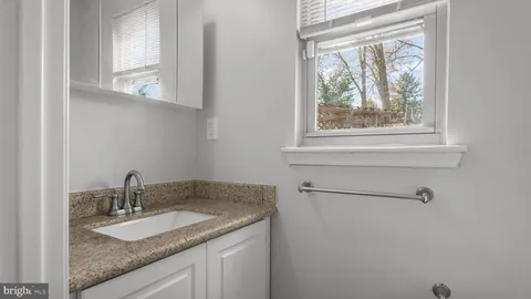 a bathroom with a granite countertop sink and a window