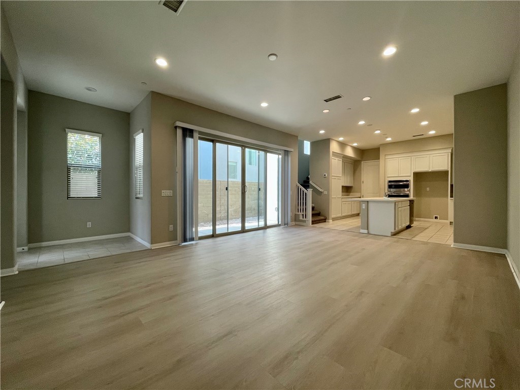 164 Spectacle Irvine, CA 92618 - Photo 4 of 21 a view of an empty room with wooden floor and a kitchen