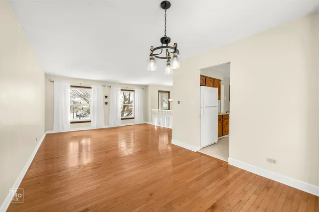 a view of an empty room with wooden floor and windows