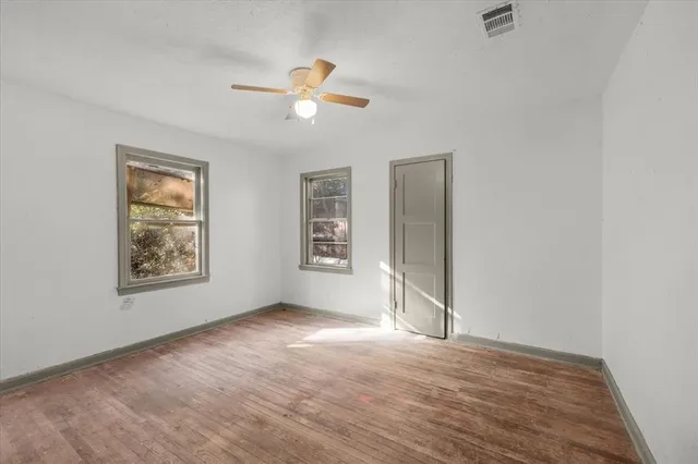 an empty room with windows and fan