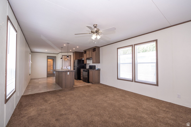 2491 Highway 89, Unit 403 Pleasant View, UT 84404 - Photo 4 of 32 Open-concept living area featuring a kitchen island with pendant lighting, integrated black appliances, wood-finish cabinetry, and a ceiling fan