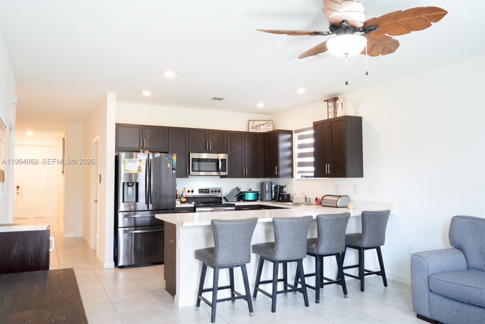 13321 Southwest 284th Street Homestead, FL 33033 - Photo 4 of 30 a kitchen with stainless steel appliances a dining table chairs and a refrigerator
