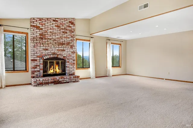 a view of an empty room with a fireplace and a window