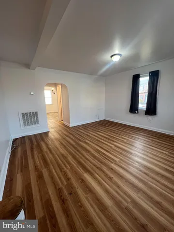 a view of empty room with window and wooden floor
