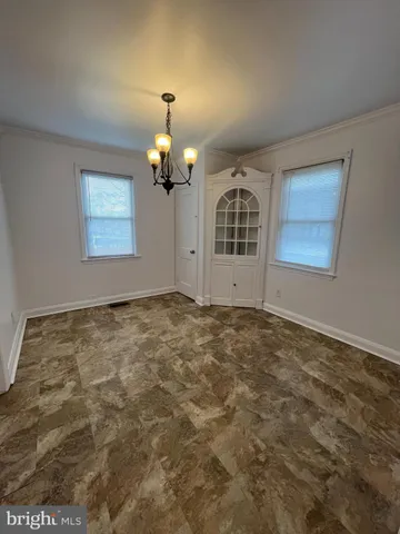 an empty room with a chandelier fan and windows