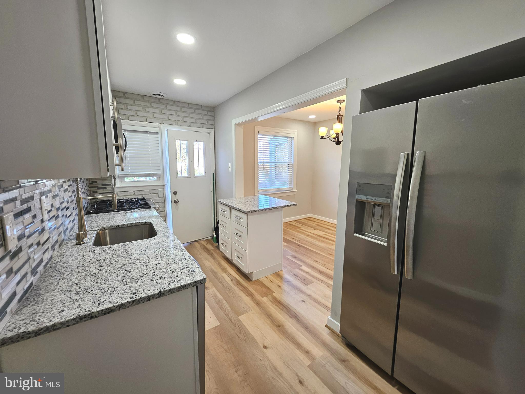 4546 Mountview Road Baltimore, MD 21229 - Photo 19 of 45 a kitchen with stainless steel appliances granite countertop a refrigerator a oven and white cabinets with wooden floor