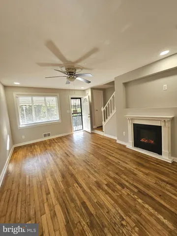 an empty room with wooden floor fireplace and windows