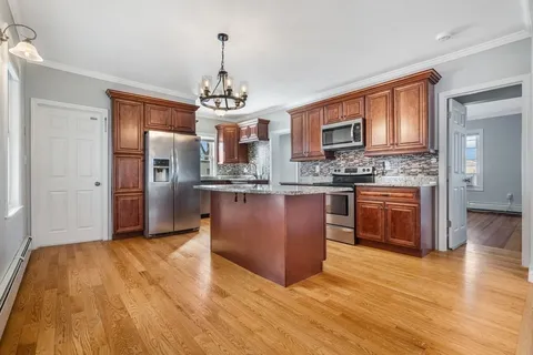 a large kitchen with stainless steel appliances granite countertop a stove a sink dishwasher a refrigerator and a wooden cabinets