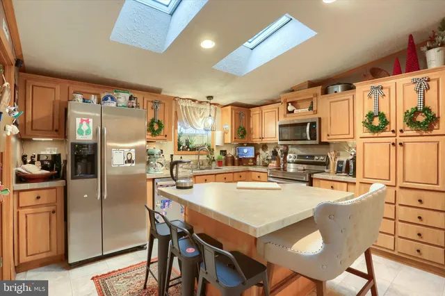 a kitchen with stainless steel appliances granite countertop a refrigerator a stove top oven a sink dishwasher and white cabinets with wooden floor