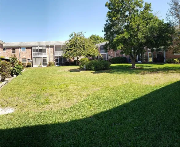 a view of a house with a big yard and large trees