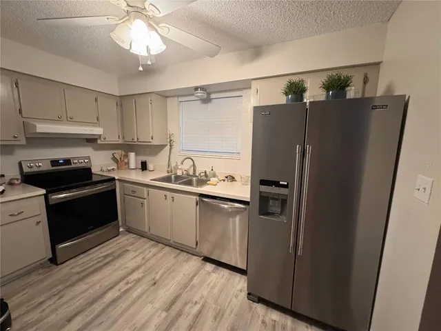 a kitchen with stainless steel appliances a refrigerator a sink and white cabinets